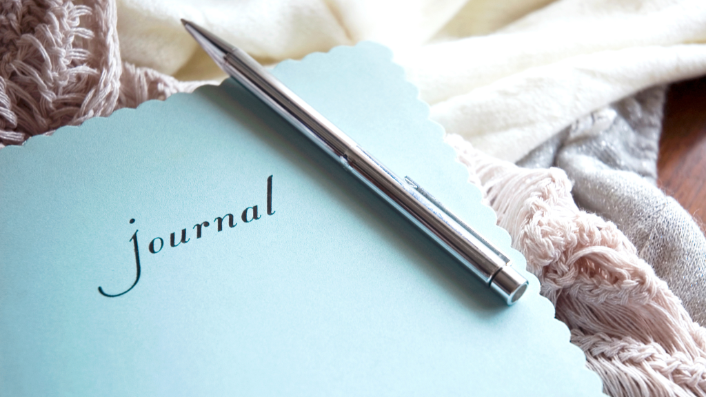 A journal lying on a blanket with a pen ready to write